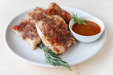 Fried turkey or chicken breast served with orange sauce and rosemary on a plate, light concrete background. Healthy food.
