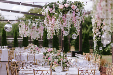 Gold chairs and tables decorated with natural pink and green flowers, candles and gold frames. Hanging flower beds and light bulbs
Wedding decoration and decor, floristic concept