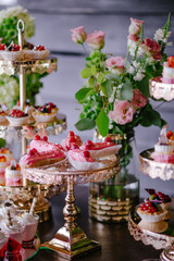 Wedding decoration of a candy bar in pink and green colors. Eclairs and panna cotta. Fresh flowers for the holiday. Sweets and tasty. Celebration and floristic concept