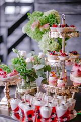 Wedding decoration of a candy bar in pink and green colors. Eclairs and panna cotta. Fresh flowers for the holiday. Sweets and tasty. Celebration and floristic concept
