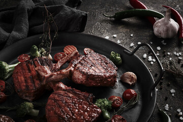 Piece of appetizing pork steak on the bone with vegetables in vintage style.