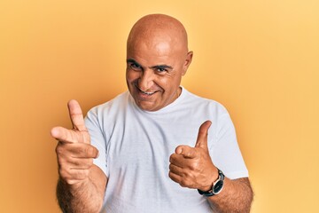 Mature middle east man wearing casual white tshirt pointing fingers to camera with happy and funny face. good energy and vibes.