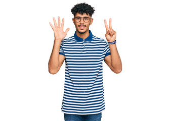 Young arab man wearing casual clothes and glasses showing and pointing up with fingers number seven while smiling confident and happy.