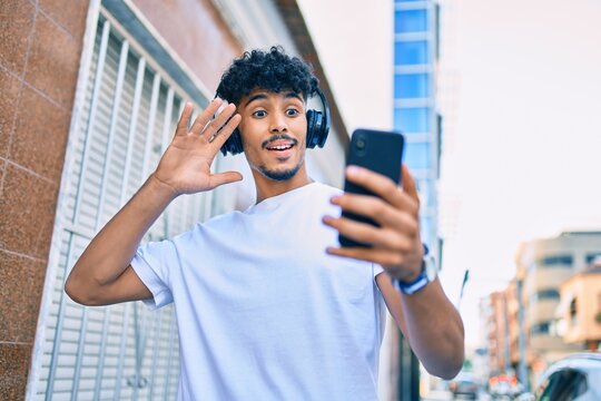 Young arab man smiling happy doing video call using smartphone walking at city.