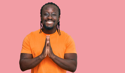 Handsome young african american man wearing casual clothes praying with hands together asking for forgiveness smiling confident.