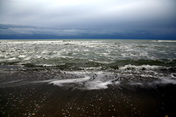 Series of waves retreating after breaking on the shore under a stormy sky