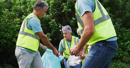 Caucasian multi generation group of male and female volunteers picking up litter in a field