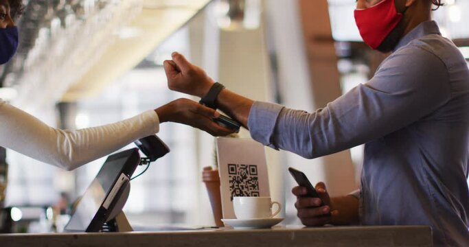 Mixed race man giving african american female cafe worker his smartwatch in order to pay