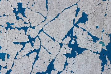 Peeling paint on the wall. Old concrete wall with cracked flaking paint. Weathered rough painted surface with patterns of cracks and peeling. Grunge texture for background and design. High resolution.