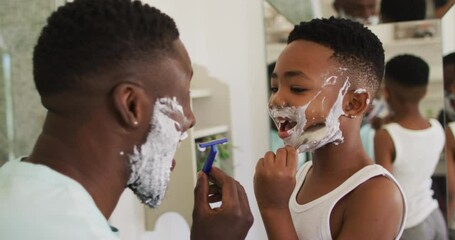African american father and son shaving together - Powered by Adobe