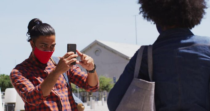 Diverse colleagues wearing face masks taking photos using a smartphone