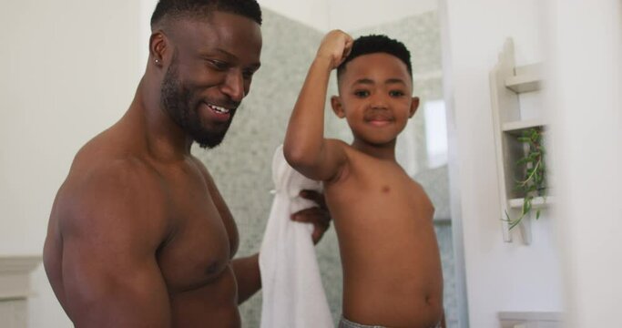 African american father and son flexing their muscles in mirror taking selfie together