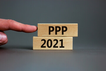 PPP, paycheck protection program 2021 symbol. Concept words PPP, paycheck protection program 2021 on wooden blocks on a beautiful grey backgrounds. Businessman hand. Business, PPP 2021 concept.