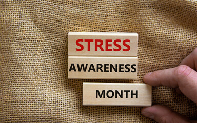 Stress awareness month symbol. Wooden blocks with words 'Stress awareness month'. Beautiful canvas background. Doctor hand. Psychological, business and stress awareness month concept. Copy space.