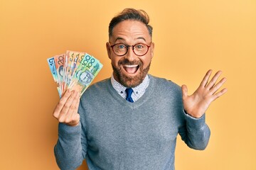 Handsome middle age man holding australian dollars celebrating achievement with happy smile and...