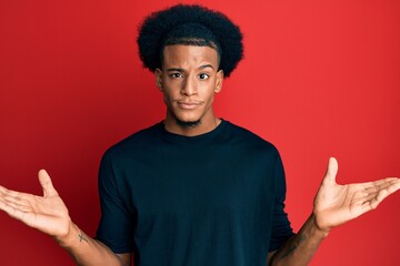 African american man with afro hair wearing casual clothes clueless and confused with open arms, no idea and doubtful face.