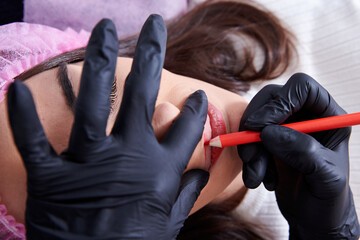 Closeup shot of a woman preparing to undergo the procedure of lip blushing with a tattoo machine