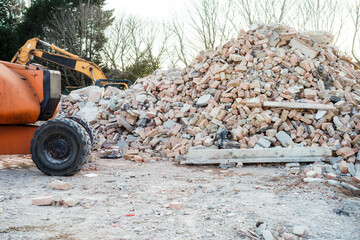 Excavator removes construction waste after building demolition. Building rubble, bricks, stones....