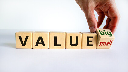 Small or big value symbol. Businessman turns wooden cubes and changes words 'value small' to 'value big'. Beautiful white background, copy space. Business and small or big value concept.