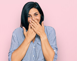 Young caucasian woman wearing casual clothes laughing and embarrassed giggle covering mouth with...