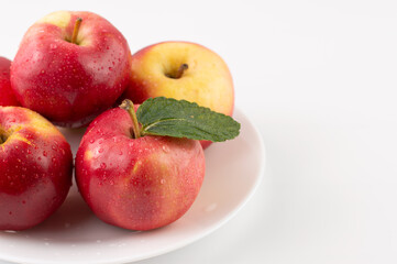 On a light background with space for writing text in a white plate, red apples.