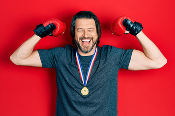 Middle age caucasian man wearing first place medal on boxing competition smiling and laughing hard out loud because funny crazy joke.