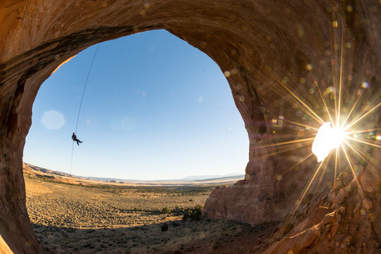 A woman rappelling into the Looking Glass Arch, La Sal, Utah.