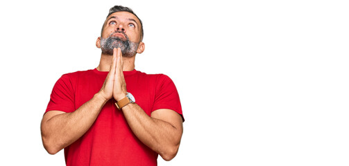Fototapeta na wymiar Middle age handsome man wearing casual clothes begging and praying with hands together with hope expression on face very emotional and worried. begging.