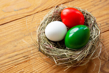 Happy Easter holiday background, Easter eggs as the color of the Italian flag - green, white, red in nest.