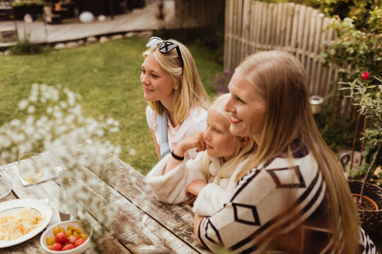 Smiling mother and daughters sitting in back yard