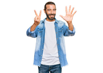 Attractive man with long hair and beard wearing casual denim jacket showing and pointing up with fingers number seven while smiling confident and happy.