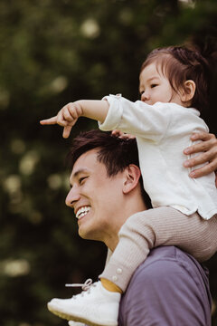 Male toddler pointing while sitting on father's shoulder at playground