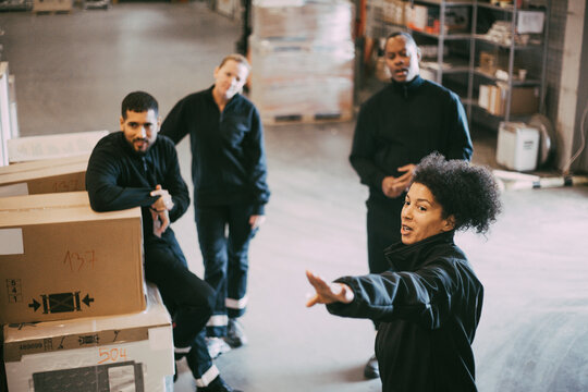 Businesswoman discussing with male and female colleagues during meeting in warehouse