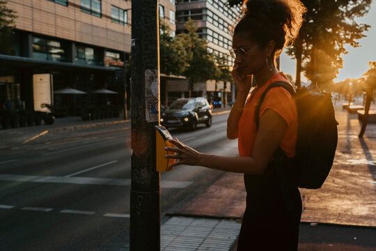 Side view of businesswoman pressing button on footpath while crossing street in city