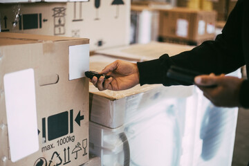 Cropped hands of manual worker scanning on package with bar code reader at warehouse