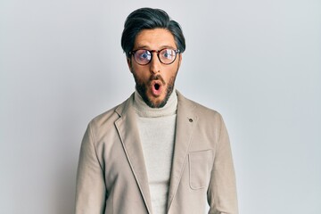 Young hispanic man wearing business jacket and glasses afraid and shocked with surprise expression, fear and excited face.