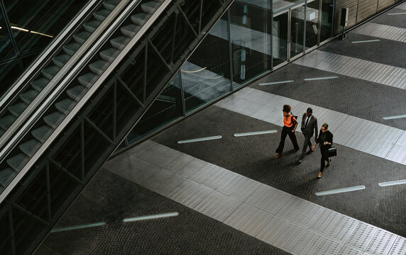Male entrepreneur with female colleagues discussing while walking by escalator