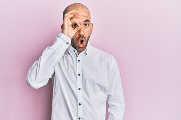 Young hispanic man wearing casual clothes doing ok gesture shocked with surprised face, eye looking through fingers. unbelieving expression.