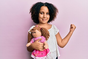 Young little girl with afro hair holding animal doll toy screaming proud, celebrating victory and...
