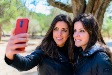 Jóvenes hermanas gemelas haciéndose un selfie con el teléfono movil. 