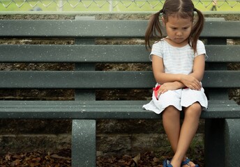 A depressed sad frustrated little girl sitting alone. Social anxiety and stressed children.