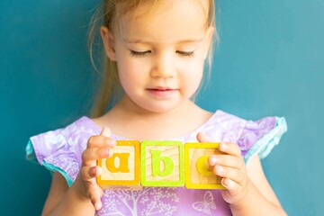 A little girl playing with alphabet blocks. Children learning abc.