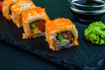 Sushi roll philadelphia with salmon, rice, cheese, cucumber, avocado and caviar on a slate board. Japanese food