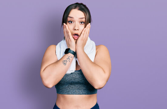 Young hispanic girl wearing sportswear and towel afraid and shocked, surprise and amazed expression with hands on face