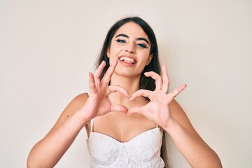 Brunette teenager girl posing elegant smiling in love doing heart symbol shape with hands. romantic concept.