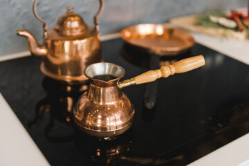 Freshly brewed coffee in golden cezve on a dark background . A golden turkey and a kettle on the...