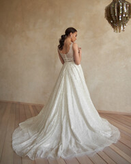 Full length bride portrait. Elegant woman with pony tail in white wedding dress spinning in beige...