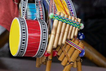 colorful and handmade musical instruments hung in a shop, detail of the drum and pan flute, close-up of the objects