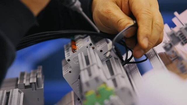 Worker's hands are screwing some connections to a patchbay