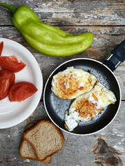 A simple breakfast on the mountain. Traditional healthy easy quick breakfast meal made of two fried eggs served on a frying pan. International simple food, top view.
